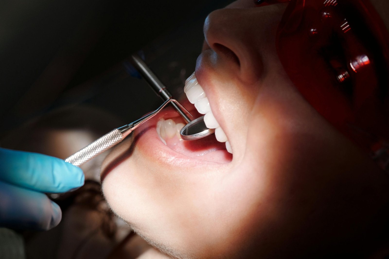 Detailed image of a dental check-up showing tools and patient wearing protective eyewear.